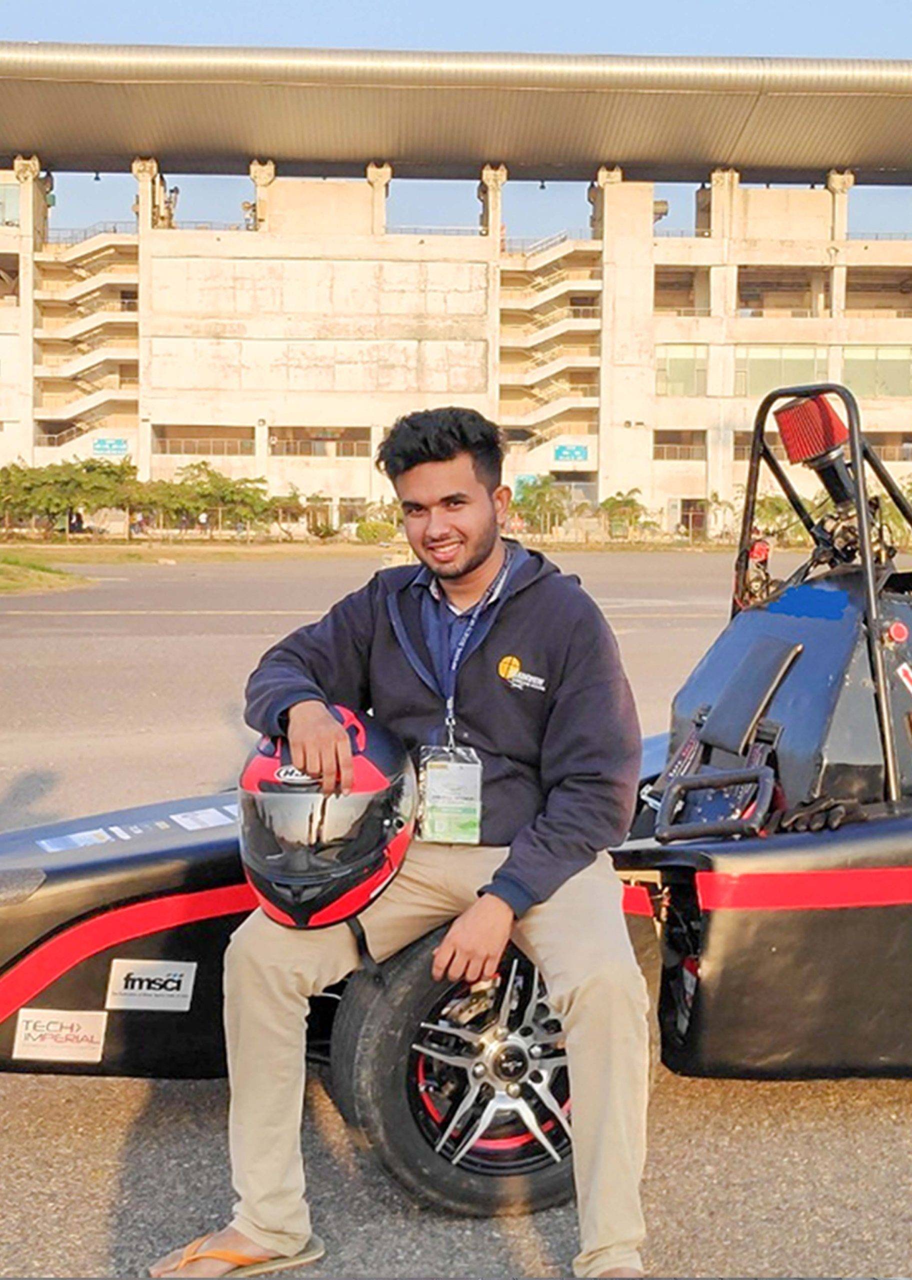 AVIT student sitting on small model racing car